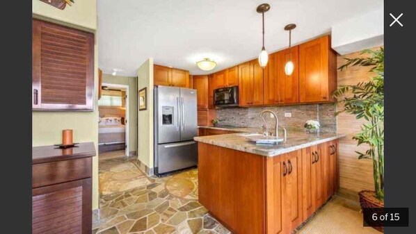 Enjoy cooking in this well-equipped kitchen with a central island, refrigerator, and microwave.