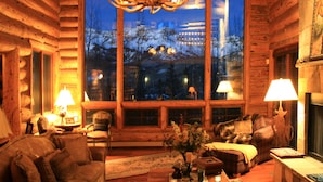 Un intérieur chaleureux de chalet en bois, avec une grande fenêtre, des meubles en bois et un éclairage doux.