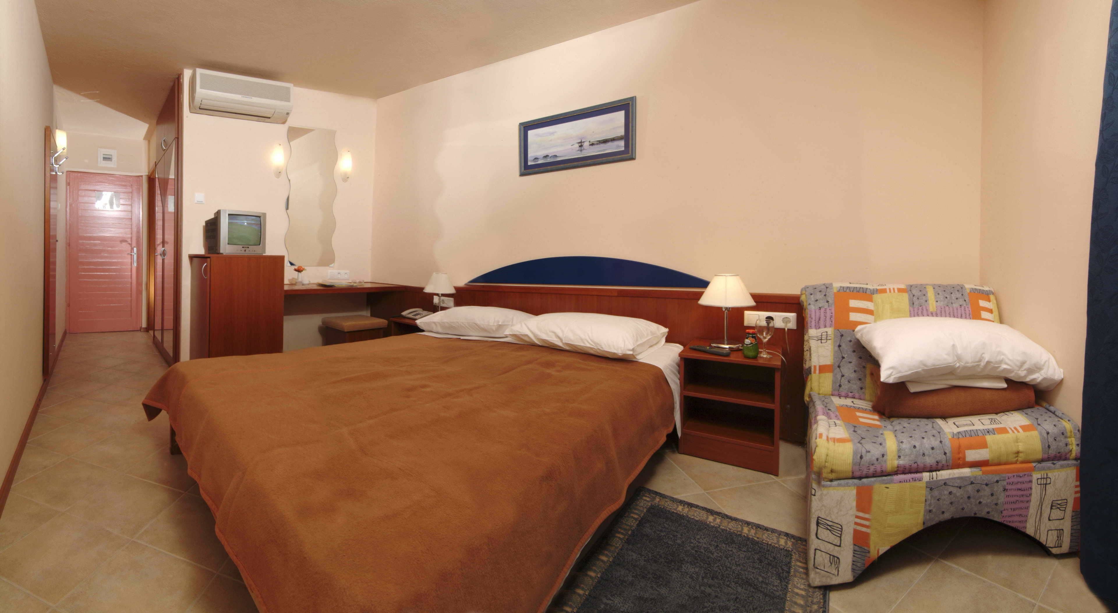 Una habitación de hotel con una cama, una silla, un escritorio y un televisor.
