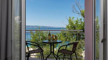 A balcony with a table and chairs, overlooking a body of water and greenery.