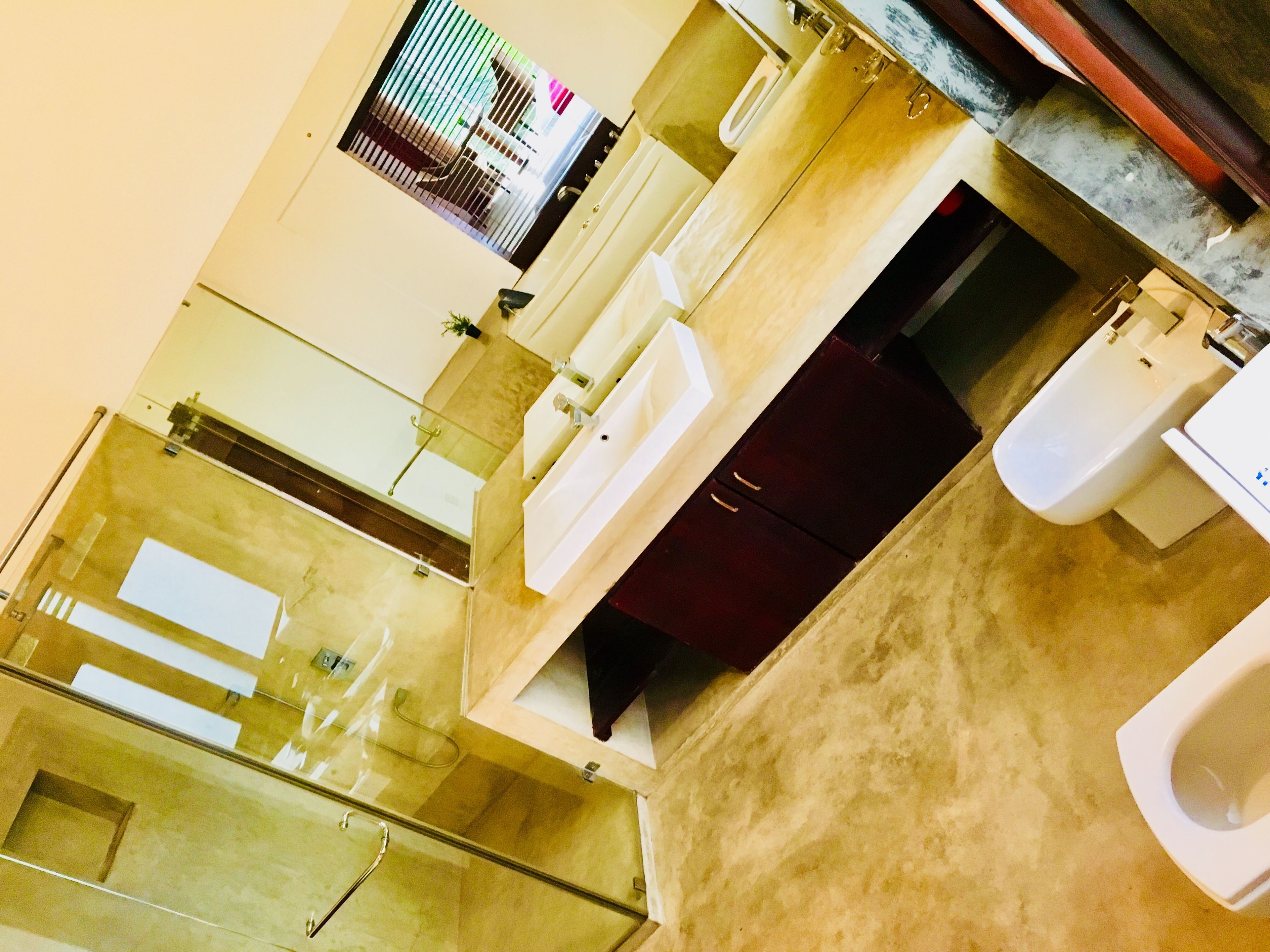 Une salle de bain moderne avec une douche à parois de verre, un meuble en bois foncé et des toilettes blanches.