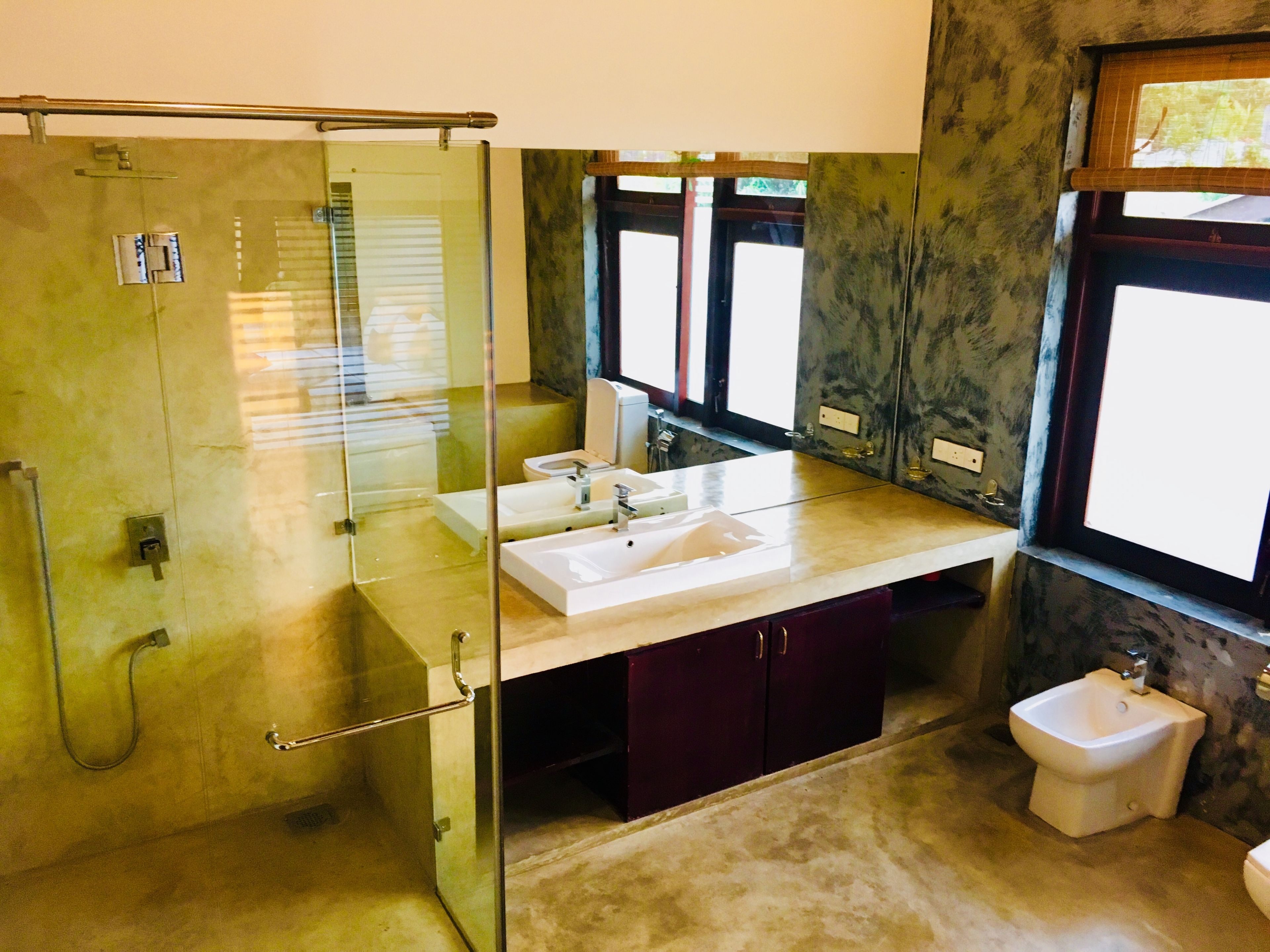 Un baño moderno con cabina de ducha de vidrio, tocador doble y un bidé.