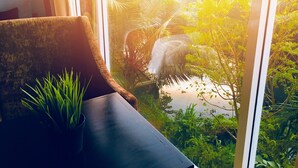 A room with a view of a lush garden through a large window. - 8 Plus  Villa (Battaramulla)