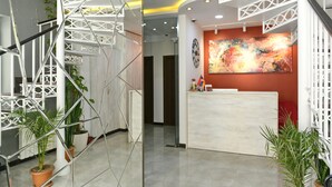 Uma área de recepção moderna com uma escada geométrica, um balcão de atendimento e uma grande pintura abstrata na parede.