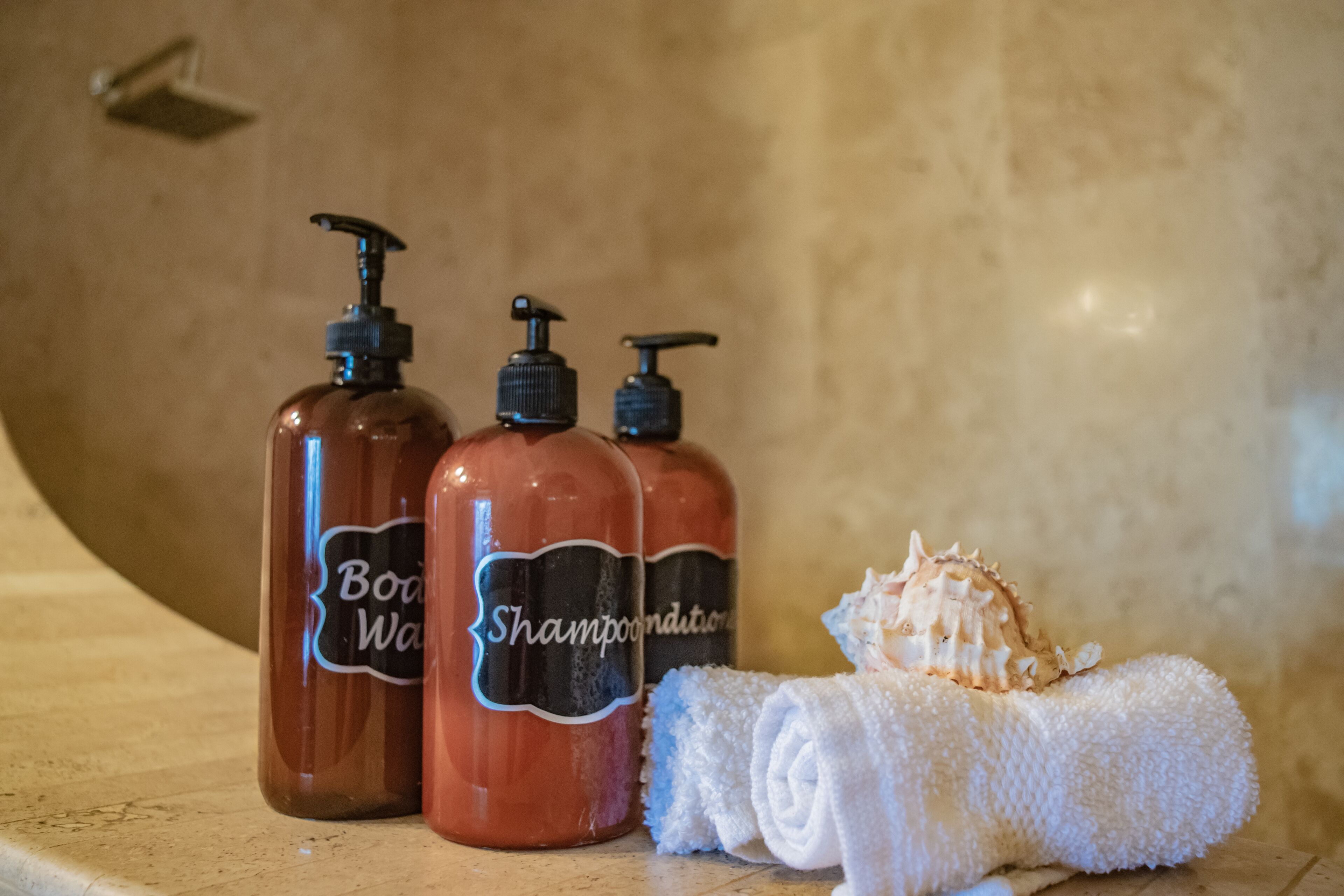 Tres botellas de jabón de baño y una toalla enrollada sobre una encimera.