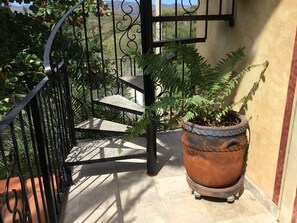 A staircase with a wrought iron railing leading to a door, surrounded by greenery and a potted plant. - Beautiful Tropical House with Ocean VIEWS! (La Cruz de Huanacaxtle)
