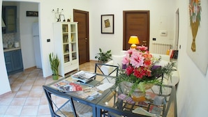 A dining area with a glass table, chairs, a white cabinet, and a potted plant. - Two apartments for groups or families up to 9 In St. Peter area, courtyard (Roma)