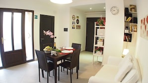 A dining area with a table set for two, a white sofa, and a bookshelf. - Two apartments for groups or families up to 9 In St. Peter area, courtyard (Roma)