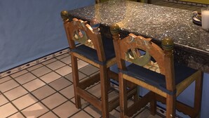 Une cuisine dotée d’un plan de travail en granit, de deux chaises en bois avec des coussins bleus, d’un sol carrelé, d’un mur jaune et d’un miroir avec un cadre décoratif.