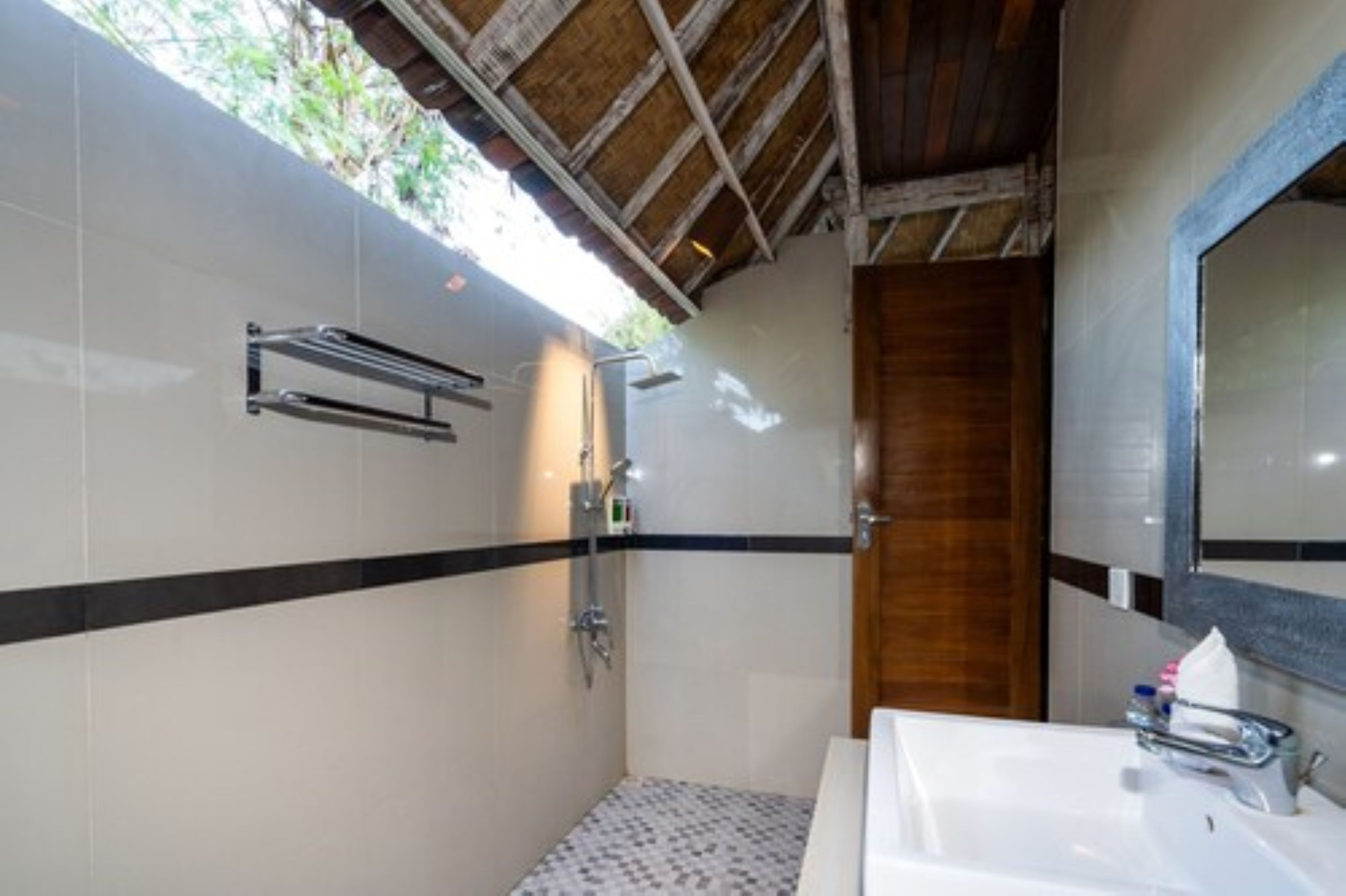A bathroom with a shower, a sink, and a wooden door.