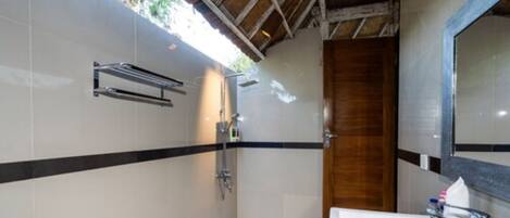 A bathroom with a shower, a sink, and a wooden door.