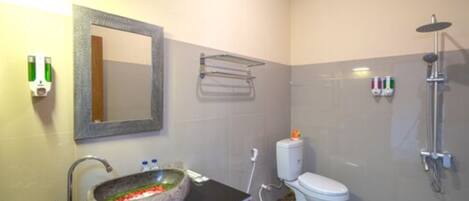 A bathroom with a stone sink, a mirror, a toilet, and a shower.