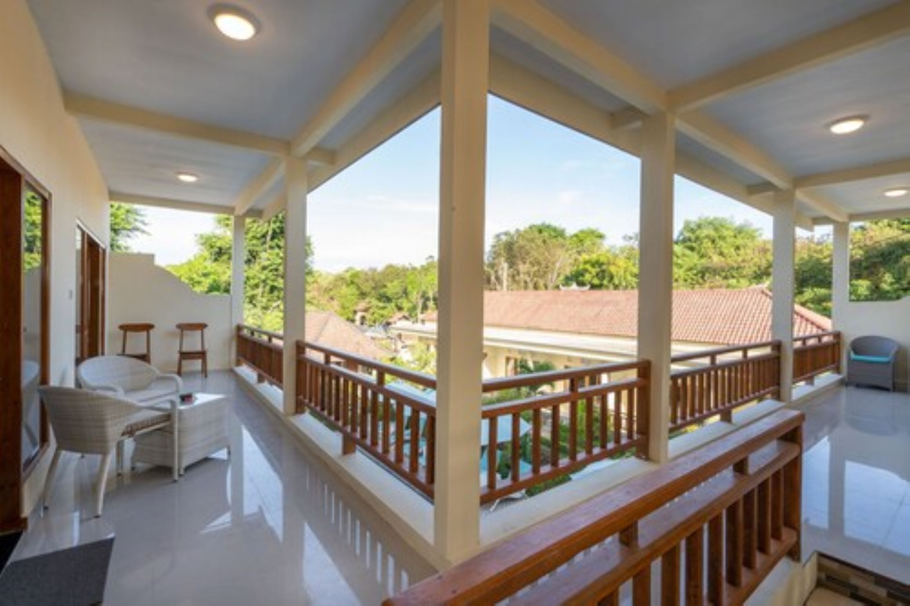 A spacious balcony with a wooden railing, a white chair, and a small table.