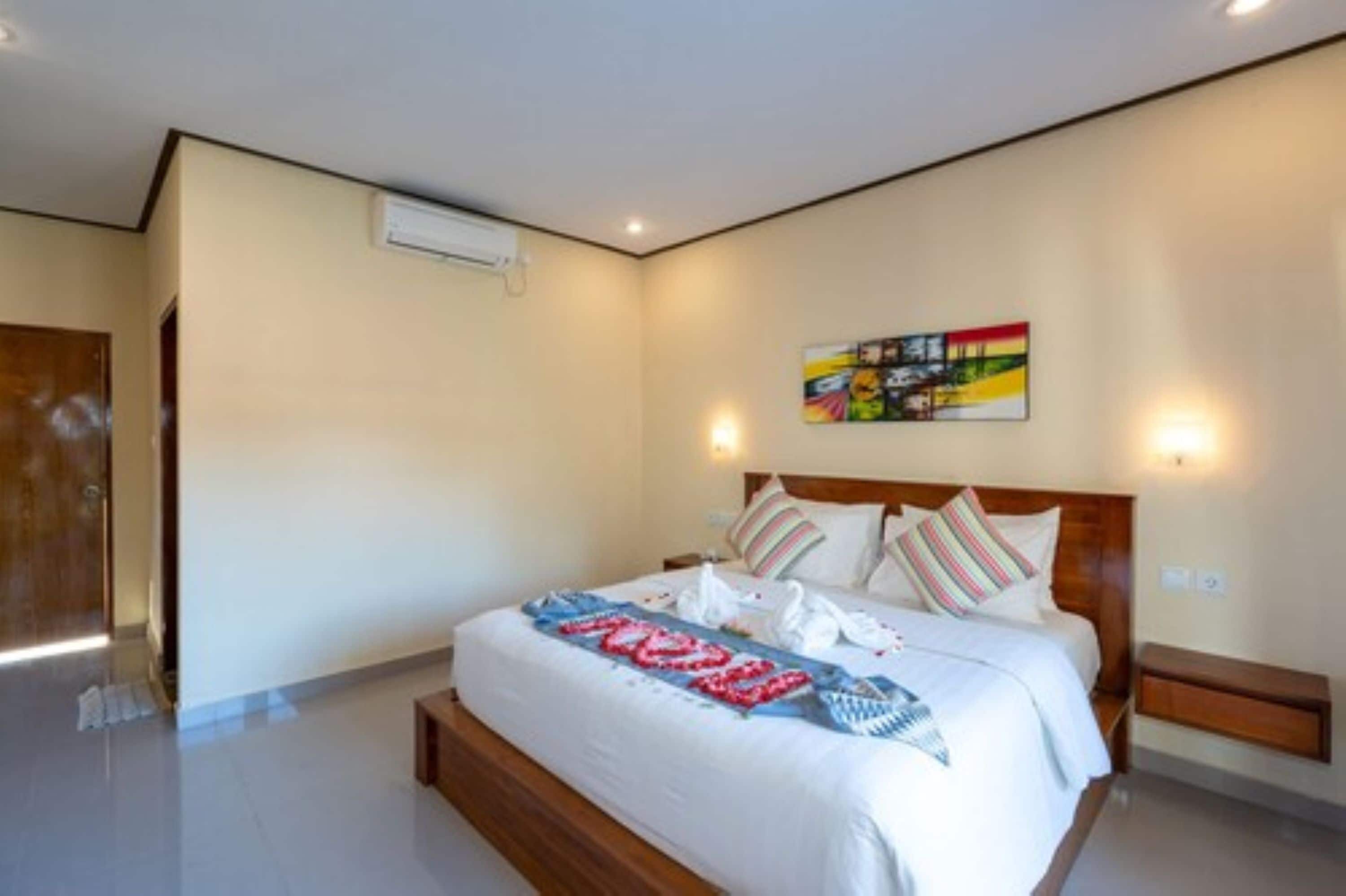 Une chambre d’hôtel moderne avec un grand lit, une tête de lit en bois et une œuvre d’art colorée accrochée au mur.