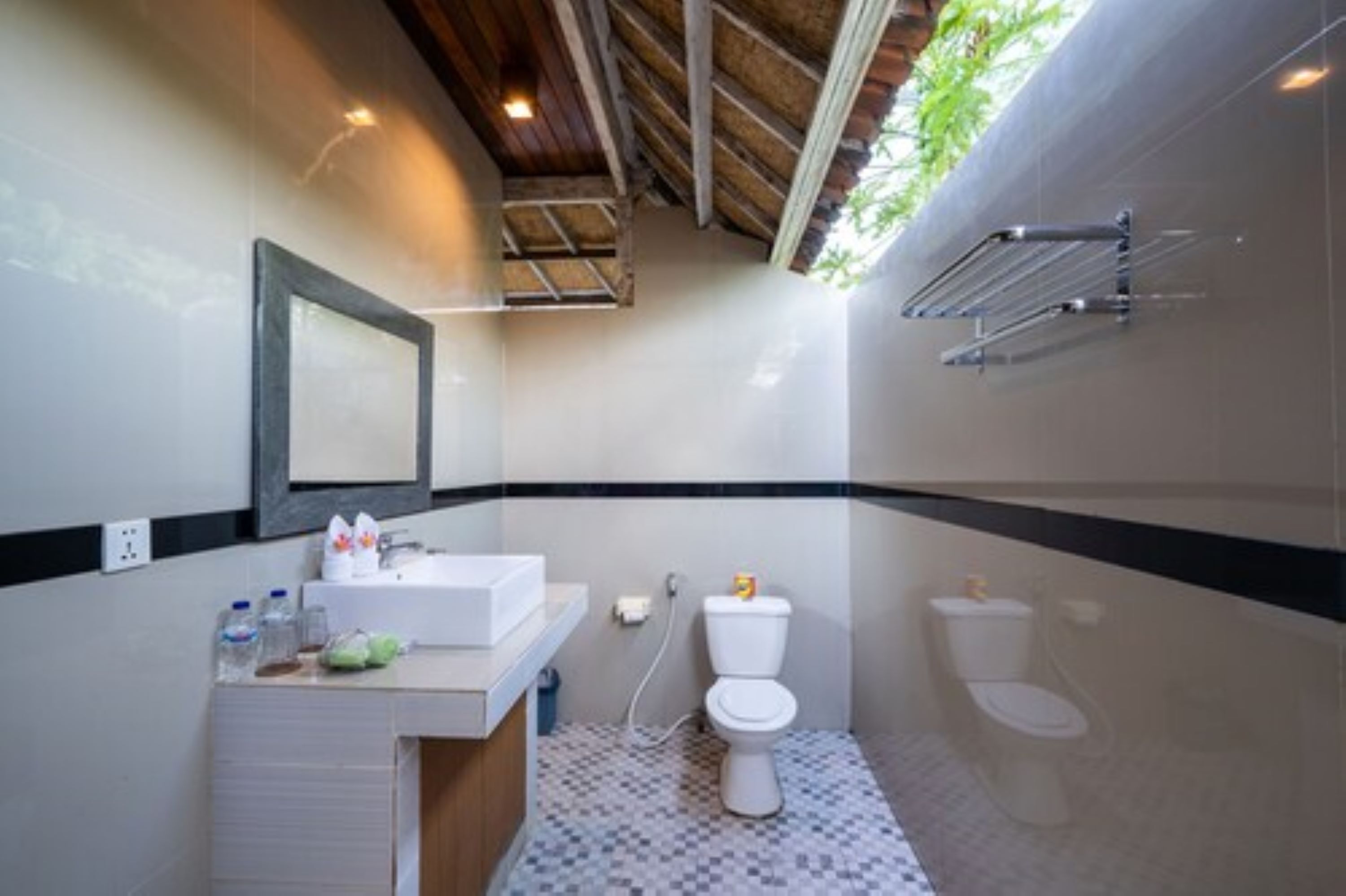 Ein Badezimmer mit einem weißen Waschbecken, zwei Toiletten, einem Spiegel und einem Handtuchhalter.