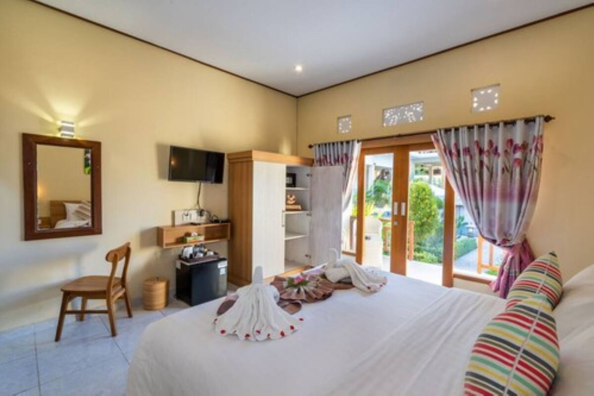 Ein Hotelzimmer mit Bett, Sessel, Fernseher, Schreibtisch und einem Fenster mit Vorhängen.