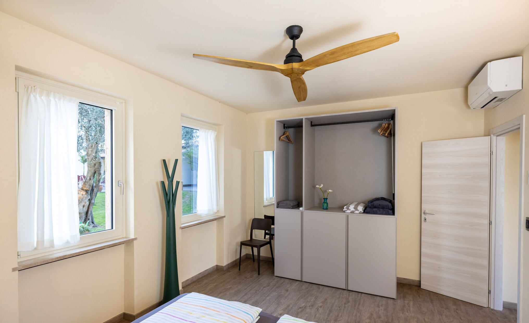 Une chambre à coucher avec un ventilateur de plafond, une armoire et un lit.