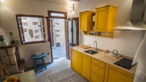 A compact kitchen with yellow cabinets, a sink, and a window with a view of the outside. - Romantic Maisonette (Chania)