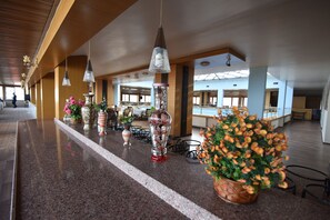 A spacious lobby with a long reception desk, multiple hanging pendant lights, and potted plants. - Saylamlar Hotel (Trabzon)