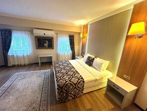 A hotel room with a bed, bedside table, lamp, and a painting on the wall. - Saylamlar Hotel (Trabzon)