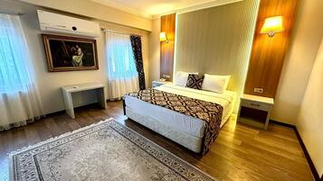 Una habitación de hotel con una cama, mesitas de noche, un escritorio, un cuadro y una alfombra estampada.