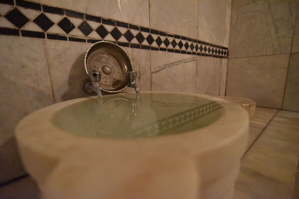 Un baño con inodoro, ducha y pared revestida de azulejos con diseño blanco y negro.
