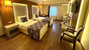 A hotel room with two beds, a desk, a chair, a TV, and a window with curtains. - Saylamlar Hotel (Trabzon)