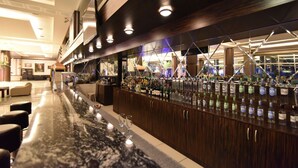 A bar area with a long counter, multiple bottles of beverages, and a seating area with chairs. - Saylamlar Hotel (Trabzon)