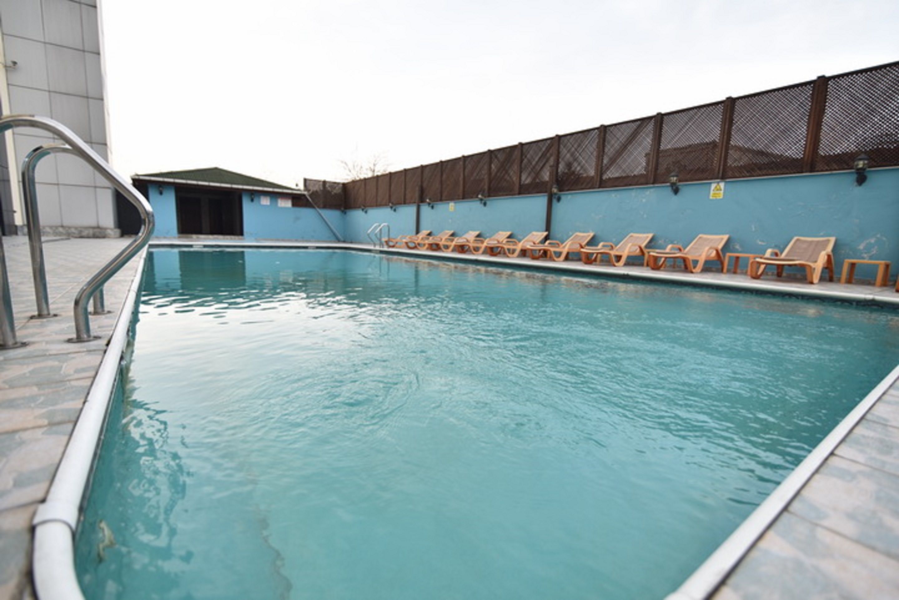 Una piscina al aire libre, sombrillas, sillones reclinables de piscina