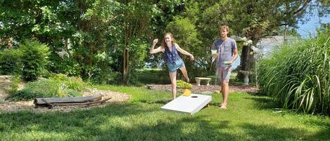 Dos personas jugando un juego al aire libre con un tablero en el suelo.