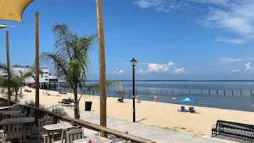 Perto da praia, areia branca, guarda-sóis, toalhas de praia