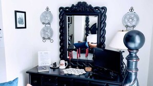 Un dormitorio con un aparador negro, un espejo, una lámpara y apliques decorativos en la pared.