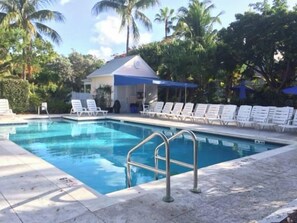 A swimming pool with lounge chairs and a small building with a blue awning.