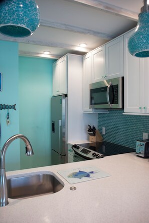 A kitchen with white cabinets, a stainless steel refrigerator, a microwave, and a stove.