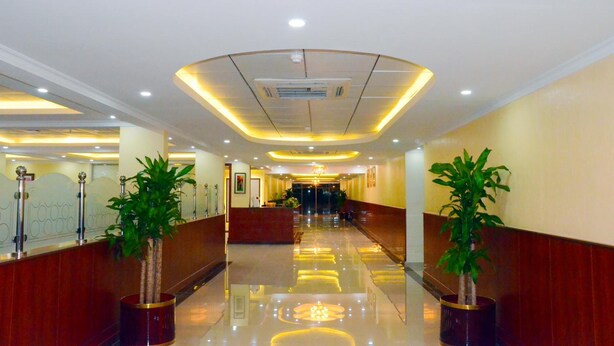 A hotel lobby with a polished floor, a reception desk, and potted plants. - Jubail Inn (Al Jubail)