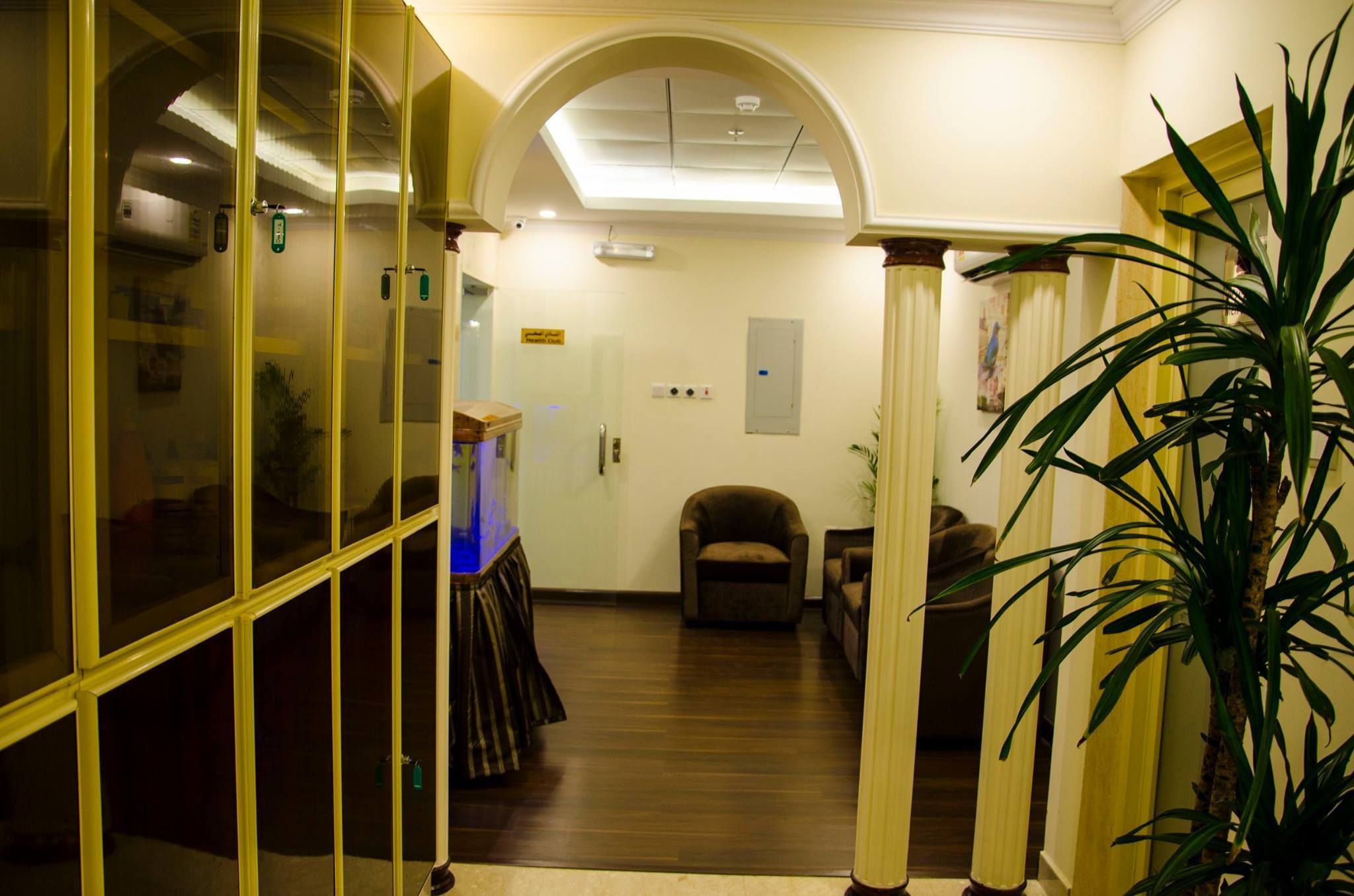 A hallway with a glass partition, a plant, and a chair.