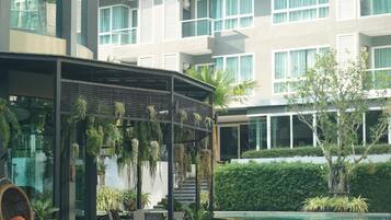 Un hotel moderno con zona de piscina, plantas de interior y un área de estar cubierta.