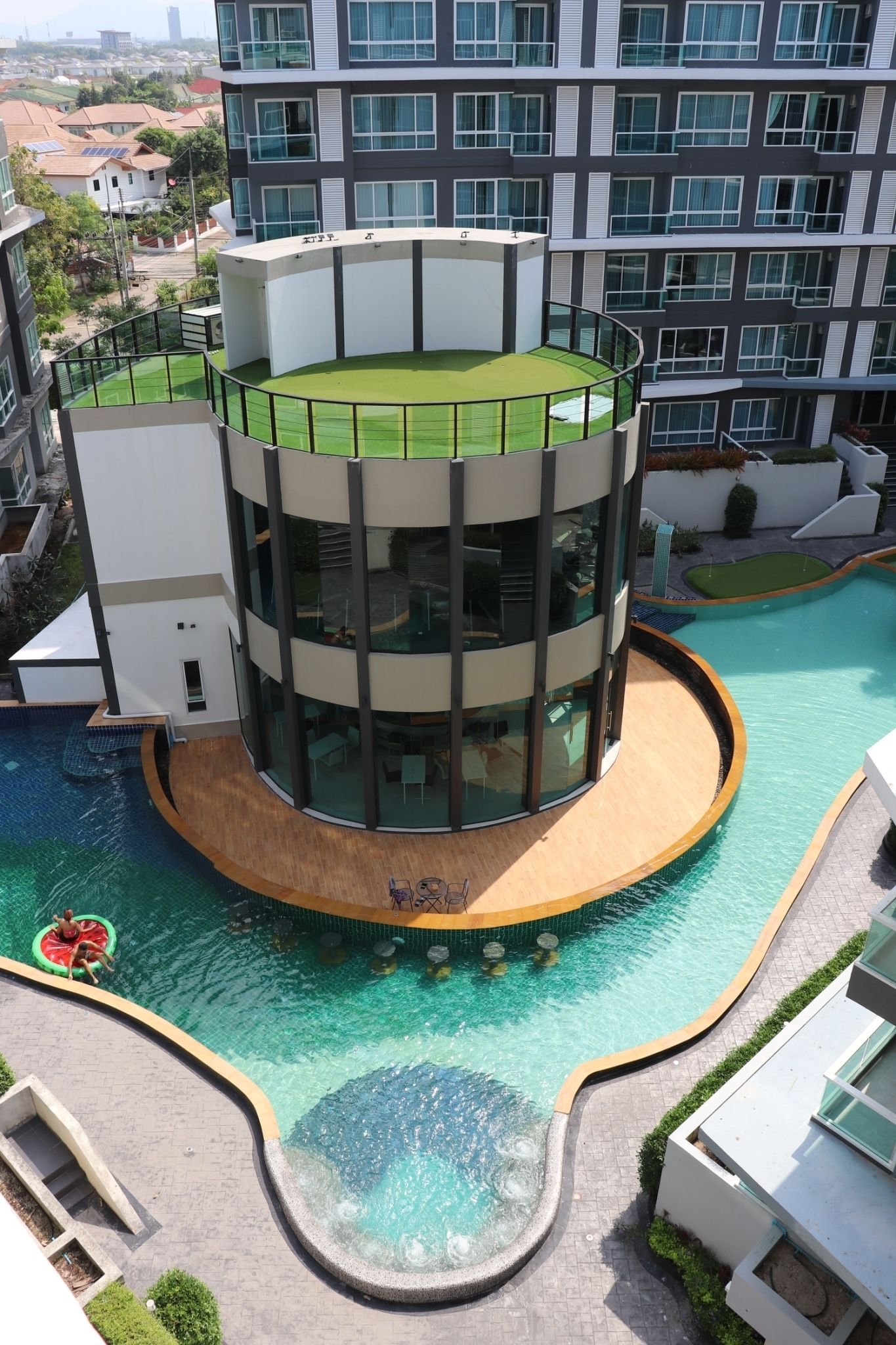 Un edificio moderno con piscina circular y jardín en la azotea.