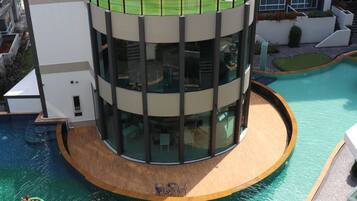 Un edificio moderno con piscina circular y jardín en la azotea.