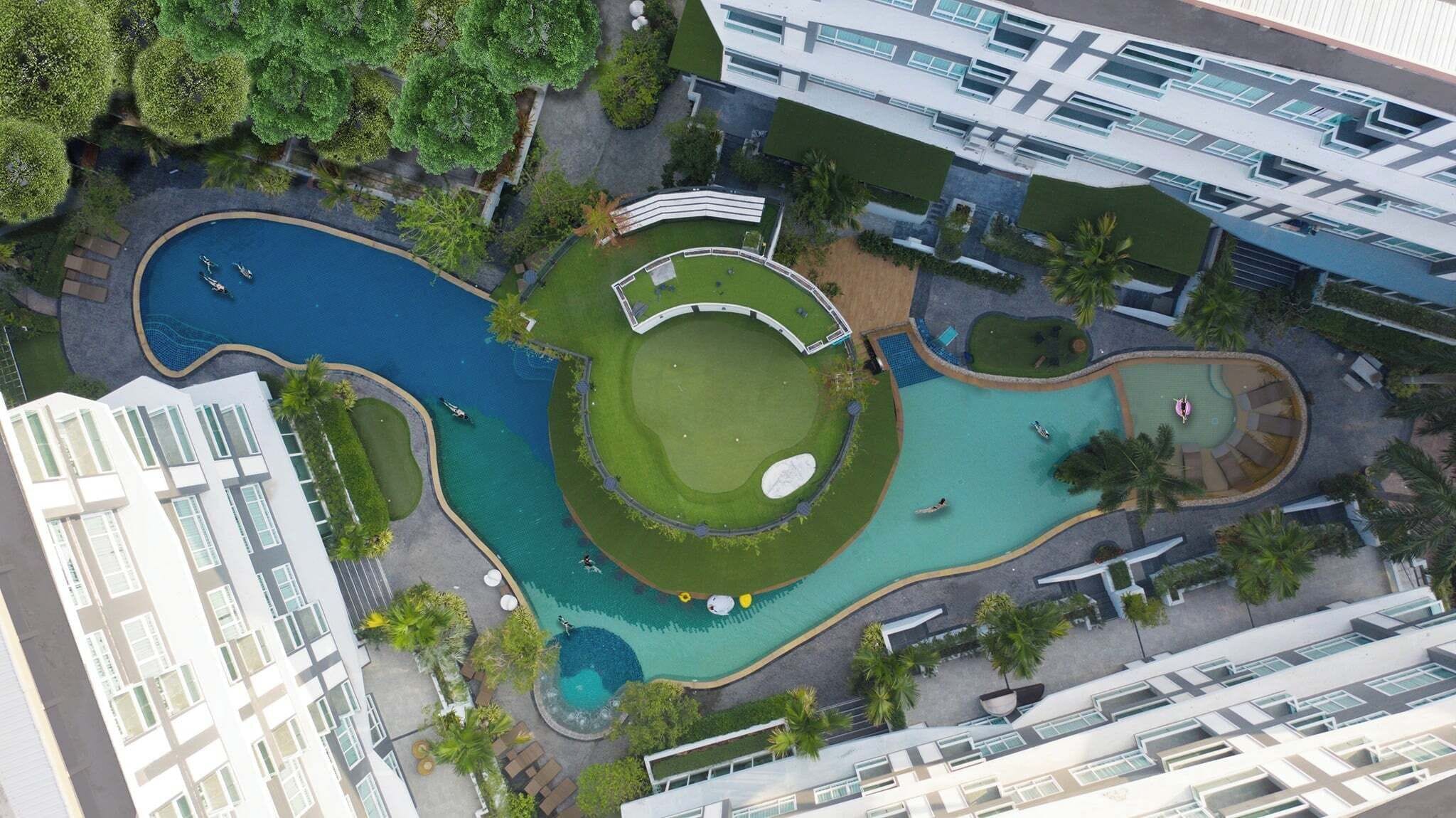 Eine Vogelperspektive eines modernen Hotels mit einem zentral gelegenen Schwimmbad, einem Golfplatz und üppiger Bepflanzung.