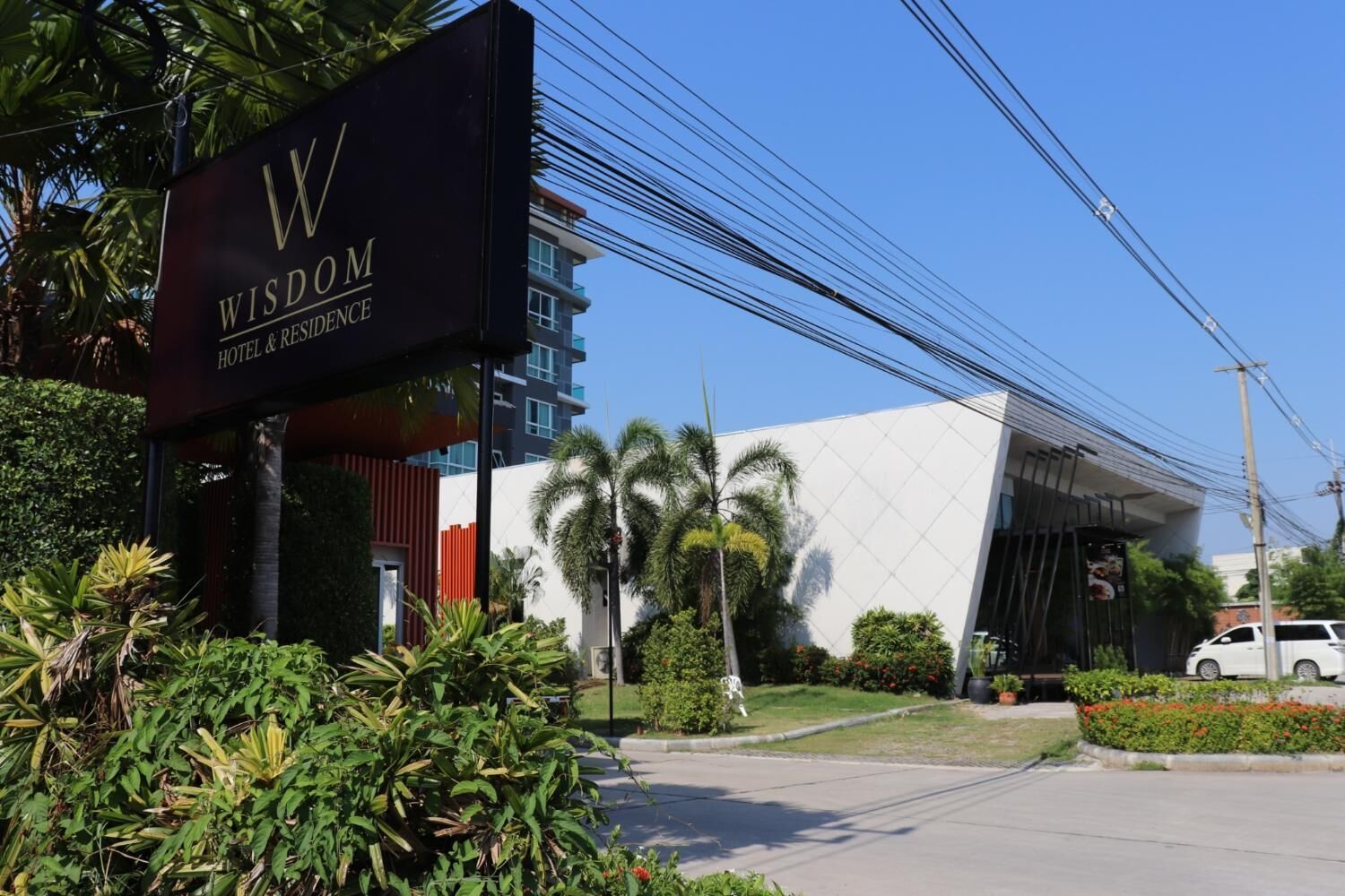 A modern hotel entrance with a prominent sign reading "WISDOM HOTEL & RESIDENCE".