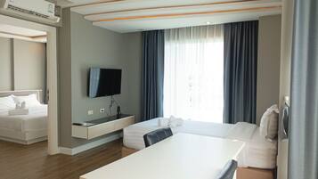 A modern hotel room with a bed, a desk, a TV, and a window with curtains.