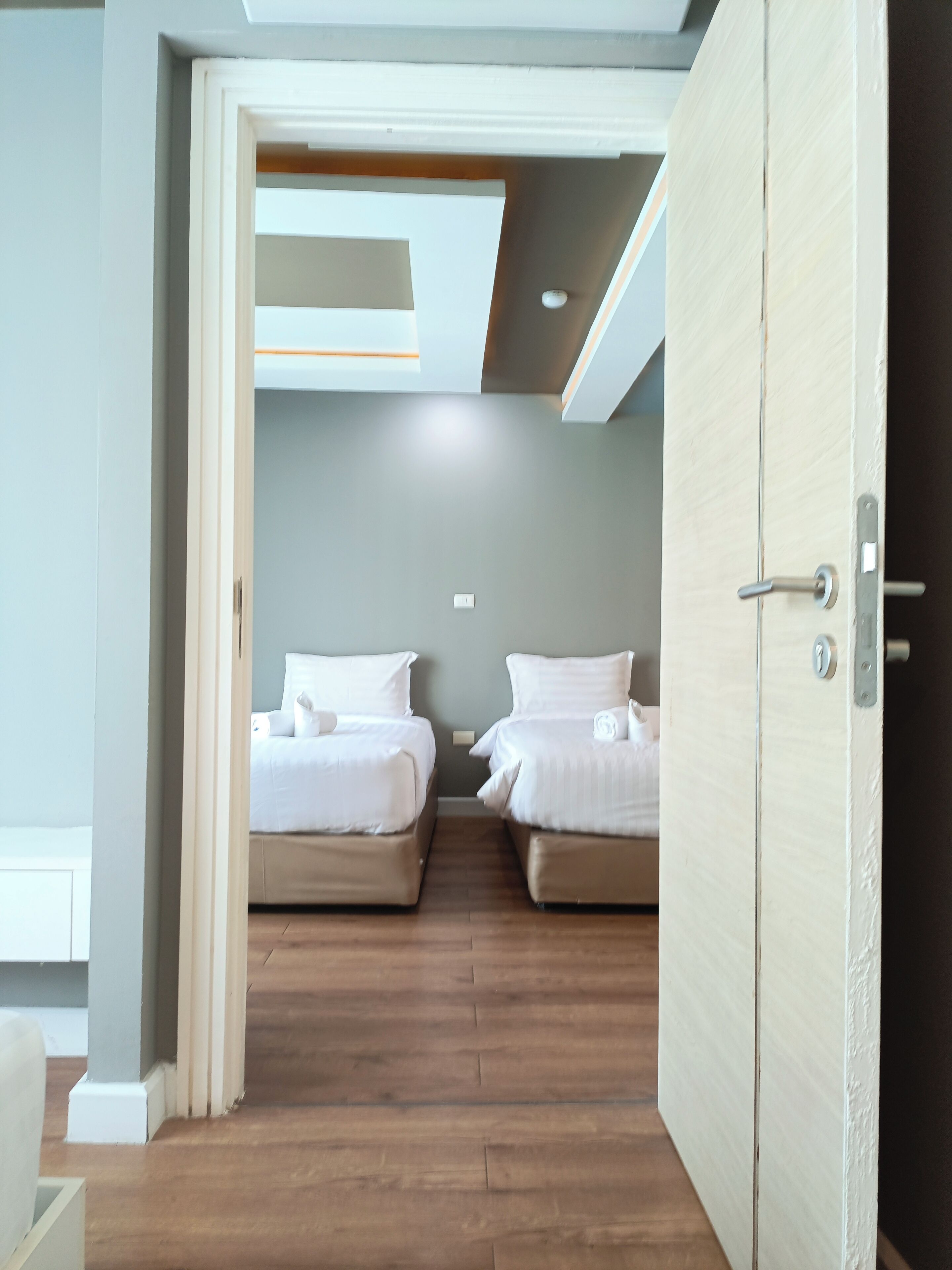 Camera d'albergo con due letti, pavimento in legno e soffitto con faretti.