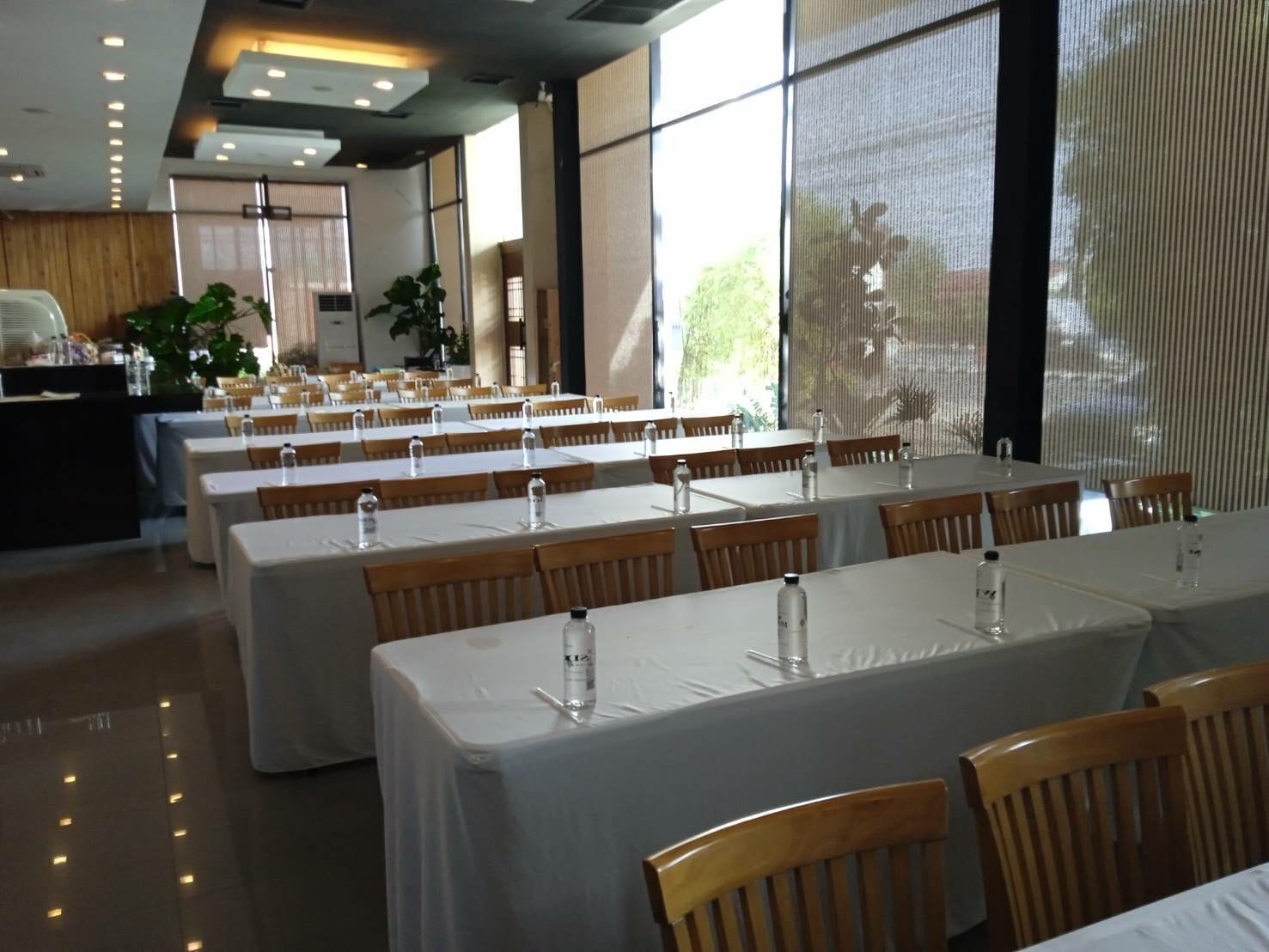 A dining area with tables set for service, large windows, and a view of the outdoors.