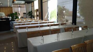 A dining area with tables set for service, large windows, and a view of the outdoors.