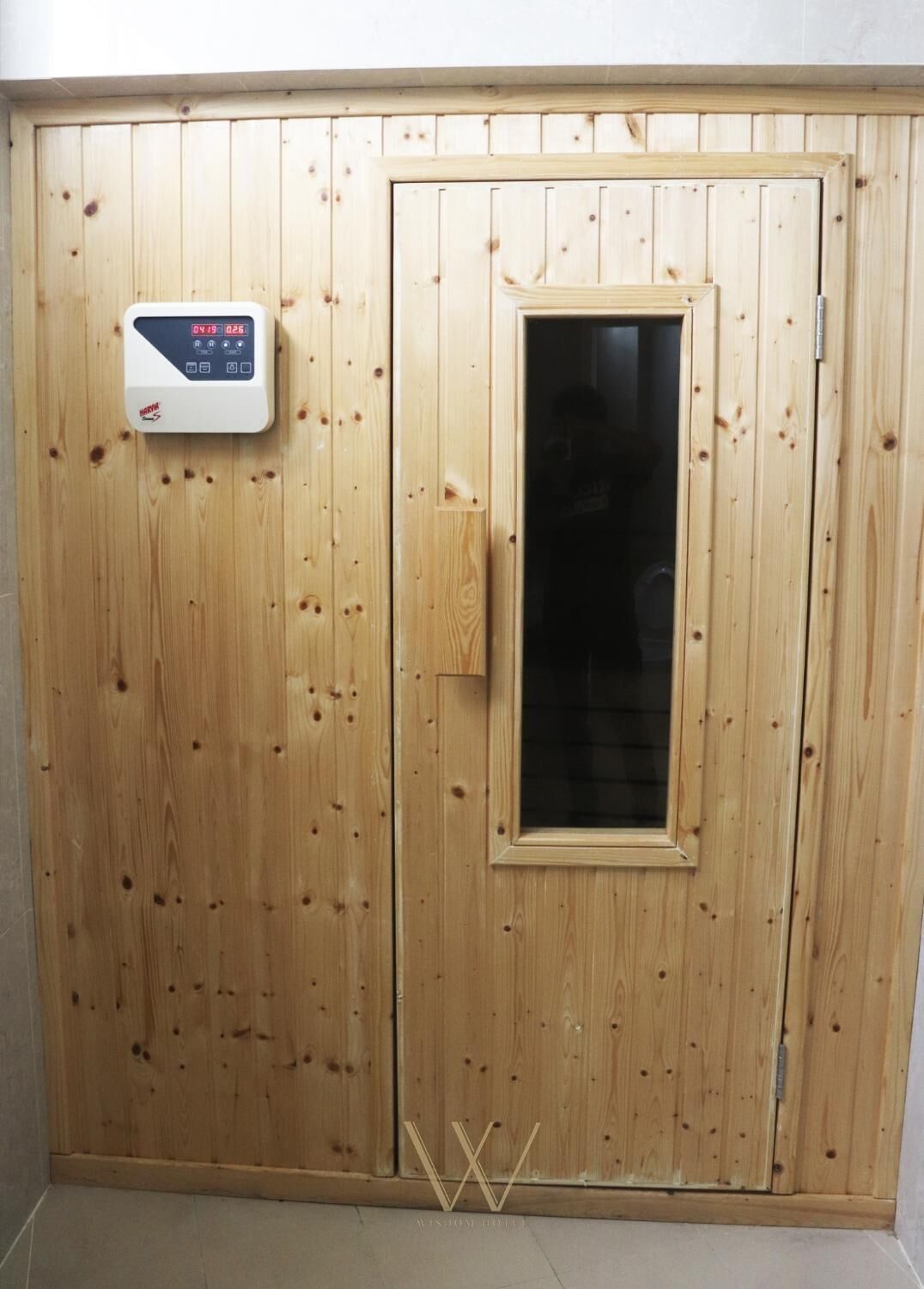 A wooden door with a digital thermostat and a small window.