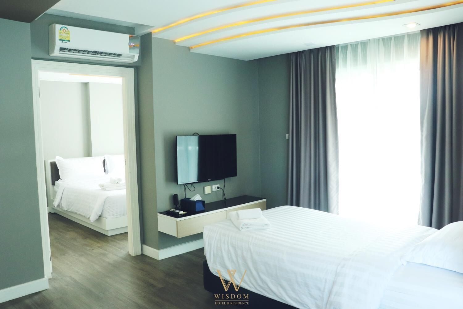 Una habitación de hotel con una cama, televisión, escritorio y aire acondicionado.