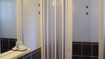 Un bagno con un lavandino bianco, uno specchio e una doccia con porta in vetro a righe.