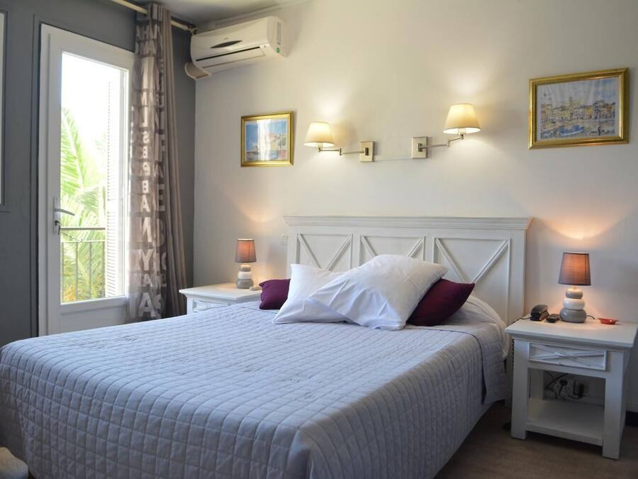 A neatly arranged bedroom with a large bed, two bedside tables with lamps, a headboard, and a window with curtains.