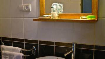 A bathroom with a white sink, a wooden vanity, a mirror with a wooden frame, and a towel rack.